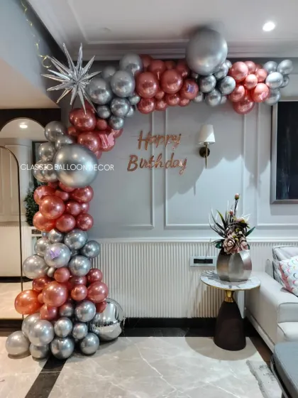An elegant home decoration featuring a rose gold and silver balloon arch, perfect for an adult birthday party.