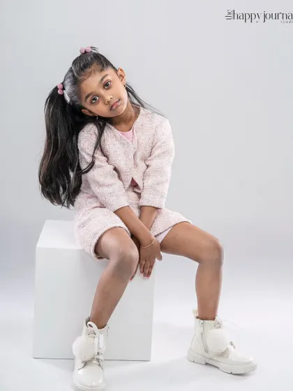 A young girl in a fashionable pink tweed outfit, striking a cool and confident pose. A perfect shot for a kids' fashion portfolio.