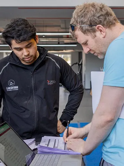 A UKSCA trainer reviews assessment paperwork with a participant, providing detailed feedback on their performance.