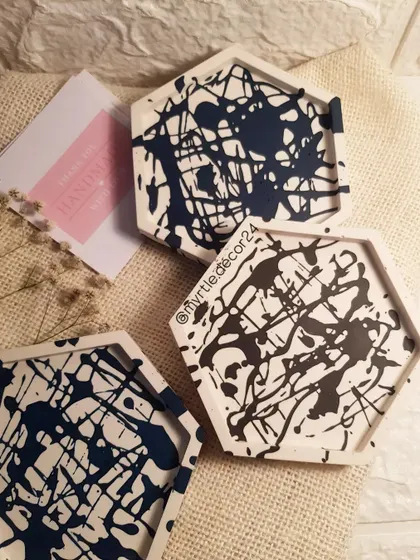 A set of three hexagon coasters with a modern black splatter design. They add an artistic touch to any coffee table.