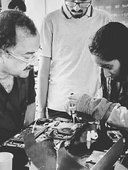 A black and white shot capturing the intense focus of a laptop repair session. Our mentors work closely with participants to solve problems together.
