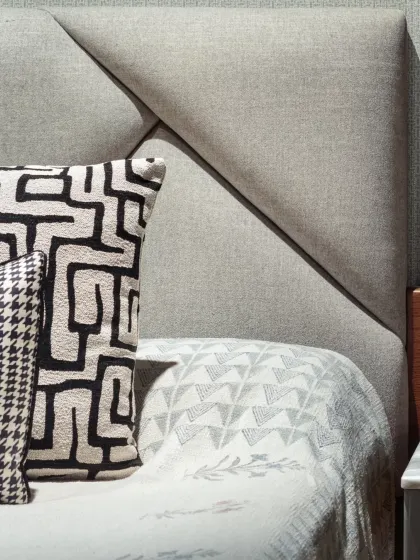 A close-up of the geometric headboard in the master bedroom. The play of texture and pattern on the cushions adds a layer of visual interest to the calm and serene sleeping space.