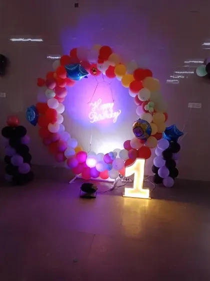 The multi-colored balloon ring under party lighting, creating a fun and festive vibe for a first birthday celebration.