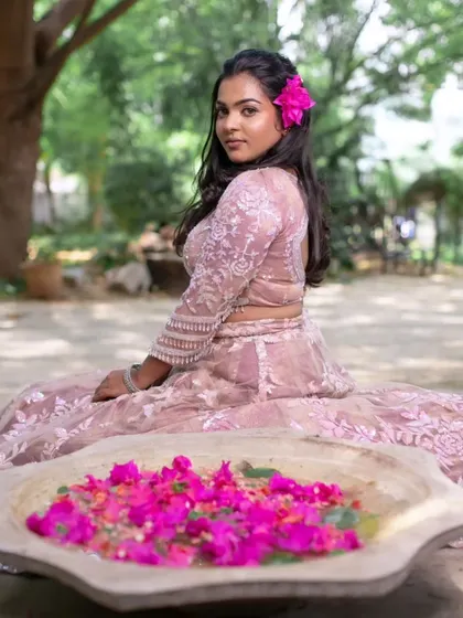 A creative shot from a model shoot, with the model sitting by a bowl of bougainvillea flowers, adding a pop of color to the scene.