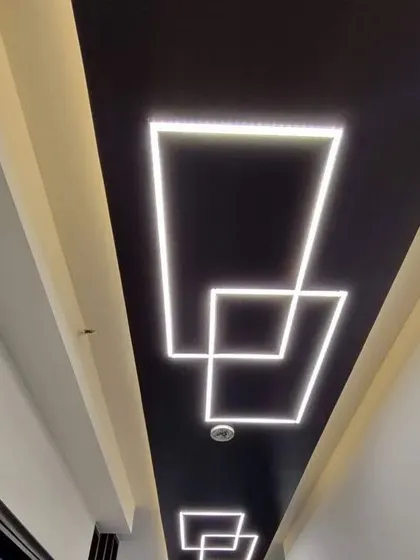 A long corridor ceiling with interlocking square patterns made from profile LEDs. The black background makes the white light pop, creating a high-contrast, futuristic look.