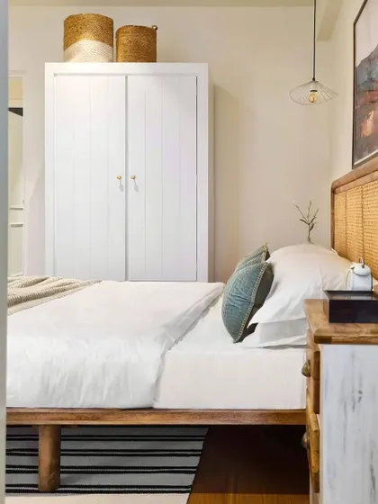 A peek into the guest bedroom, showing how I use simple, essential pieces to create a comfortable space. The vintage-style armoire provides storage, while the woven baskets on top add a rustic, textural element.
