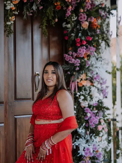 A lovely portrait of the bride, Monika, standing by a floral-decorated doorway at her reception venue.