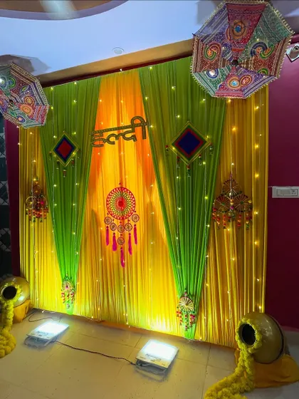 This is a classic Haldi ceremony backdrop I created. It uses vibrant yellow and green drapes, traditional embroidered umbrellas, and decorative earthen pots overflowing with marigold flowers for an authentic feel.