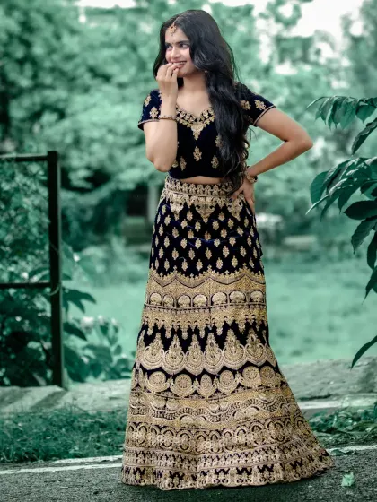A view of the back of the dark blue velvet lehenga, showing the detailed embroidery that continues all around the skirt.