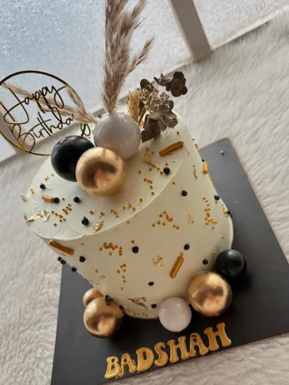 A gravity-defying cake for a birthday "Badshah." The tilted design with black, white, and gold accents creates a modern and edgy look.