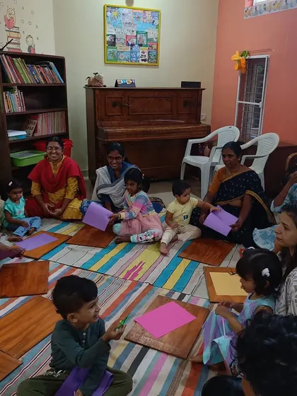 A happy, bustling craft session where children are making paper shirts, inspired by a story about an elephant.