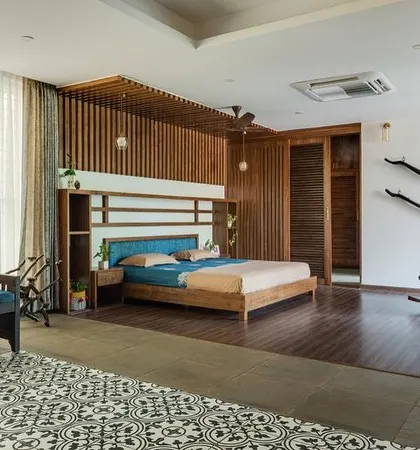 Another view of the master bedroom, showing the custom headboard with integrated shelving and the comfortable diwan for lounging. The material palette is kept warm and natural to create a restful ambiance.