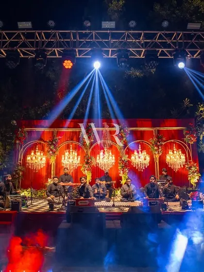 The stage for the Sufi night, where the qawwali performers are framed by a backdrop of red velvet and golden arches inset with chandeliers. The lighting design adds to the drama and soulfulness of the performance.