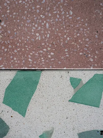 A study in contrast. This image shows a fine-grained red terrazzo next to a white Venetian terrazzo with large green stone chips, demonstrating the range of styles we can create.