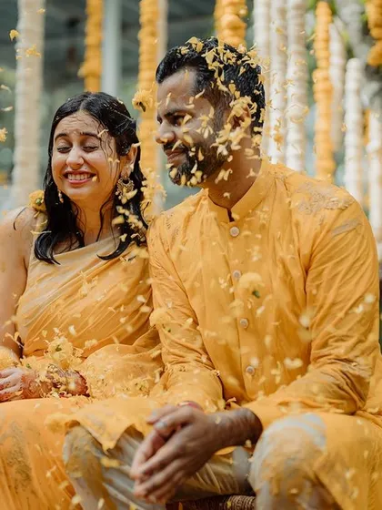 A shower of flower petals for the happy couple during their Haldi ceremony, set against a backdrop of hanging jasmine and marigold strings.