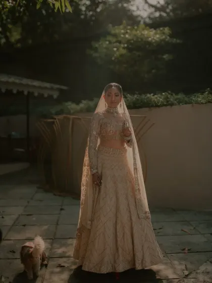 A full-length bridal portrait in the soft, golden light of the evening. The bride, along with a furry friend, looks absolutely radiant and serene.