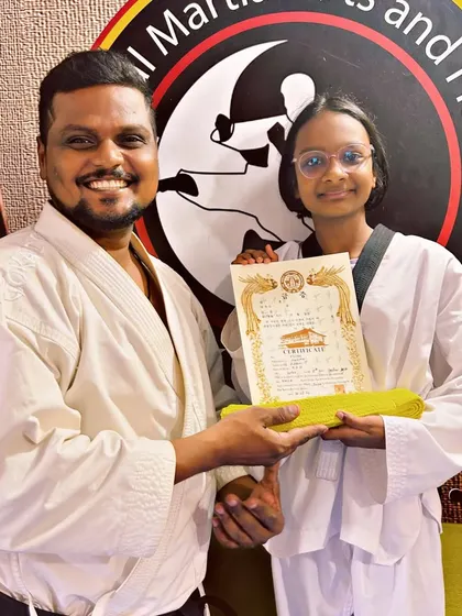 A student receives her yellow belt and certificate, marking a key milestone in her Taekwondo training and development.