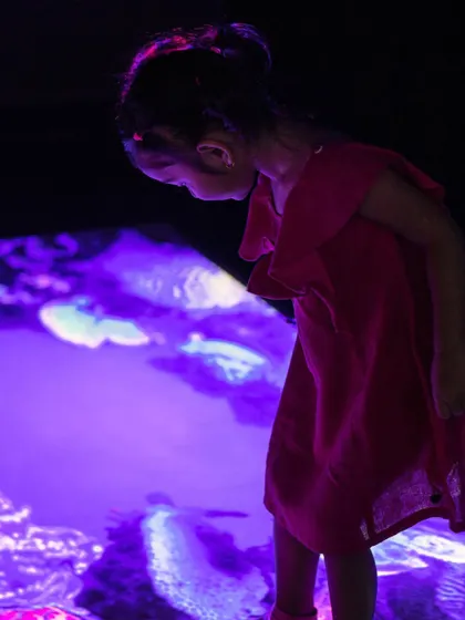 A child gazes at the interactive floor, which can transform into an underwater world right beneath her feet.