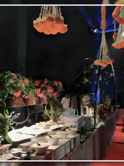 A night-time buffet detail showing hanging floral arrangements of marigolds above the food station. This adds a traditional and festive feel to the wedding celebration.