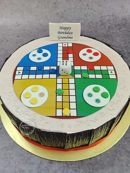 A Ludo board cake for a grandma's birthday. This strawberry-flavored cake is topped with an edible Ludo game, ready to play.