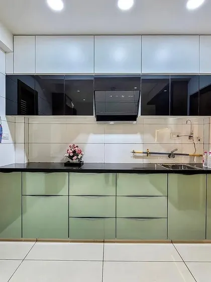 A beautiful example of a parallel kitchen with a refreshing color scheme. The light green handleless base cabinets are paired with white upper cabinets and black glass shutters for a balanced, modern look.