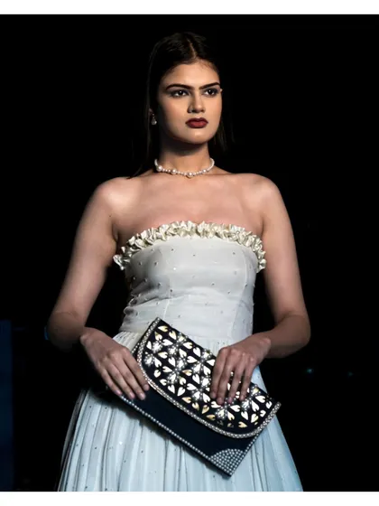This portrait showcases a model in a strapless white gown, holding an embellished clutch. Our focus here is on capturing the complete look, including accessories, which are crucial for fashion storytelling and brand collaborations.