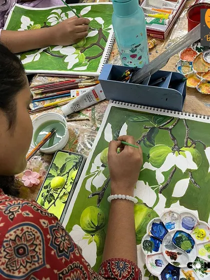 A student works on a monochrome painting of green apples. This exercise helps them see the subtle variations in a single color and how to use them to create form and depth.