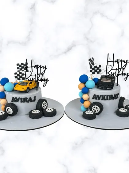 Another look at the custom race car cakes for Aviraj and Avkirat. These personalized cakes are perfect for celebrating birthdays together in style.
