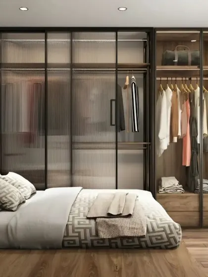 This bedroom design focuses on functionality with a large wardrobe featuring translucent glass sliding doors. A simple wooden headboard and a compact dressing table complete the space.