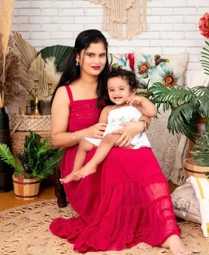 A beautiful portrait of a mother and daughter enjoying a quiet moment together. The vibrant red dress contrasts beautifully with the natural, earthy tones of the boho studio setup.