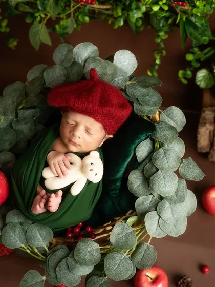 Cuddling a tiny teddy bear, this baby in a red beret is the picture of innocence. The apple and foliage props complete this creative, woodland artist theme.
