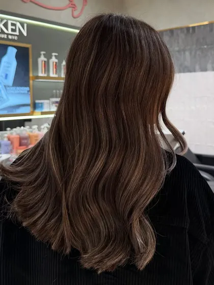 Another angle of a signature balayage, showing the beautiful blend of tones against the salon's Redken gloss bar.