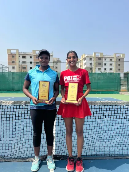 Our player, in her PBI Tennis Academy shirt, stands with her doubles partner after winning the AITA 1 Lakh Doubles Championship, a victory born from resilience.