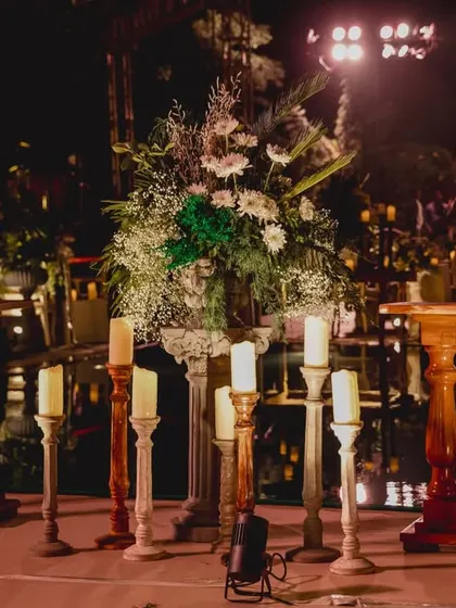 A centerpiece detail from the welcome dinner, showing a mix of white flowers and greenery surrounded by elegant candle stands.