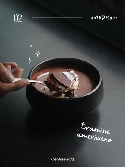 A rich, dark Tiramisu Americano from Americano. This shot uses dark, moody lighting to highlight the dessert's decadent chocolate and coffee flavors.