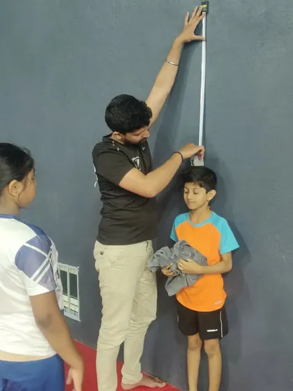 A trainer measuring the height of a young athlete as part of our regular assessments at the sports academy.