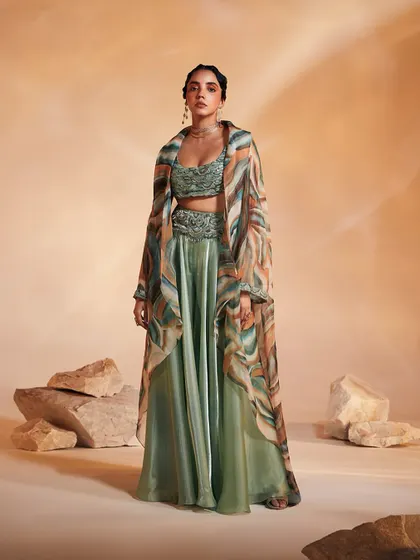 Our Adoree Cape Set balances modern prints with traditional layering. This three-piece ensemble includes a hand-adorned bustier, swirl-worthy flared pants, and an alluring oversized cape in a custom print, perfect for a statement-making entrance.