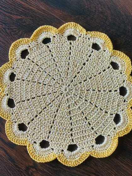 A clean, top-down shot of the beige doily with the openwork border.
