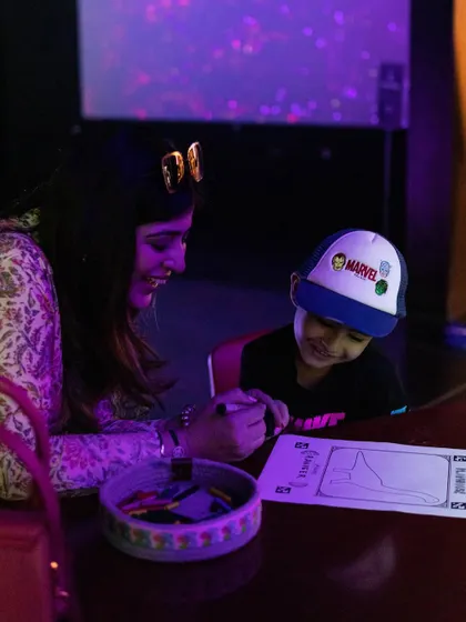 A mom helps her son with his drawing for the Virtual Draw activity, a fun bonding experience for parents and kids.