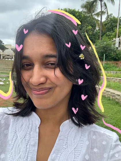 A happy selfie with some messy hair, made cuter with a sprinkle of heart doodles.