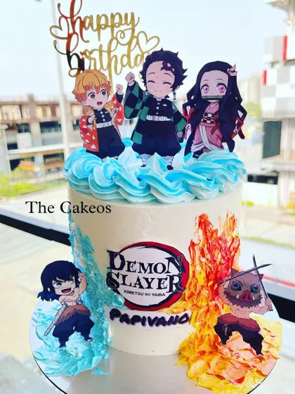 A dynamic Demon Slayer anime themed cake. The design features popular characters like Tanjiro and Nezuko, with buttercream frosting cleverly styled to look like fire and water breathing techniques.