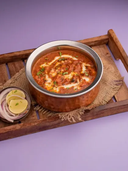 This rich and creamy paneer curry was shot with a clean, professional look for a restaurant's online menu. The simple wooden tray and side of onions add a touch of rustic charm.