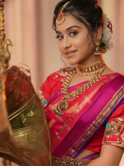 A perfect look for Varalakshmi Vratam or any festive pooja. The model is wearing a beautiful temple jewellery set that pairs wonderfully with her red and pink silk saree.