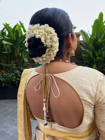 A close-up of the beautiful bridal bun adorned with fresh jasmine flowers, a classic element of the Malayalam wedding look.