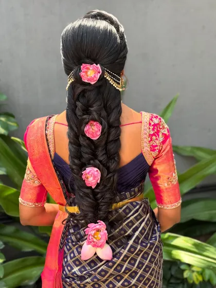 A closer look at the placement of the pink flowers on the braid. This hairstyle is a beautiful fusion of a classic braid with modern, vibrant floral accessories.