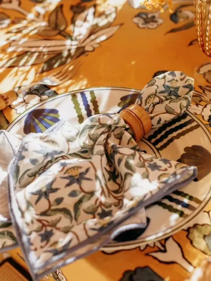 The play of light and shadow on a beautifully set table. The custom-printed napkin and plate create a cohesive and artistic look, enhanced by the warm afternoon sun.