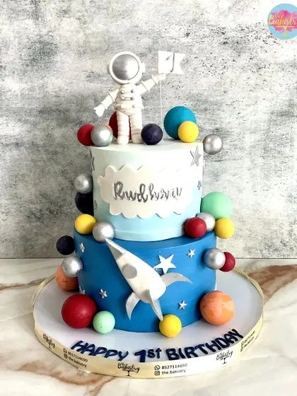 Prepare for a flavor mission that's out of this world! This two-tiered space cake for Rudhav's first birthday features an astronaut, a rocket, and colorful planets.
