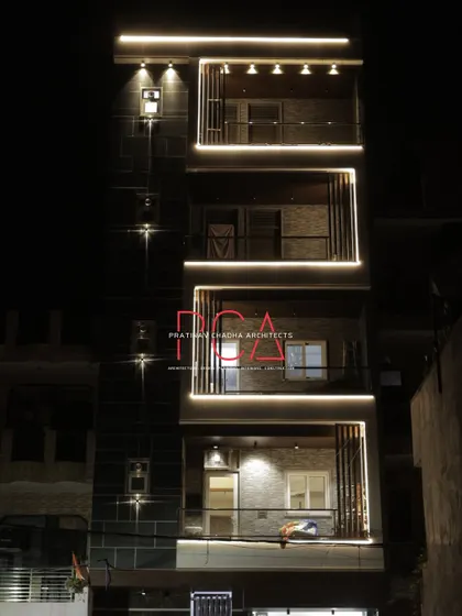 Another night view of The Cursive Abode facade, showing the warm glow of the interior spaces through the windows, adding life to the exterior.