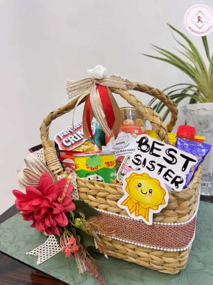 A perfect hamper for the "Best Sister". This woven basket is filled with her favorite snacks and decorated with a beautiful red flower and ribbon, making it a thoughtful Rakhi gift.