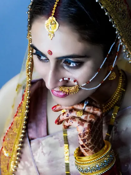 A close-up portrait of the bride, capturing the delicate details of her nath and the sparkle in her eyes.